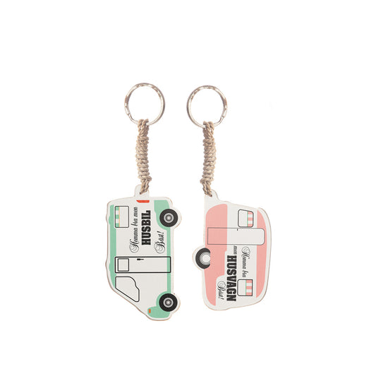 Nyckelring med texten 'Hemma bra, husvagn bäst' i rosa färg och hemma bra husbil bäst i grön färg.