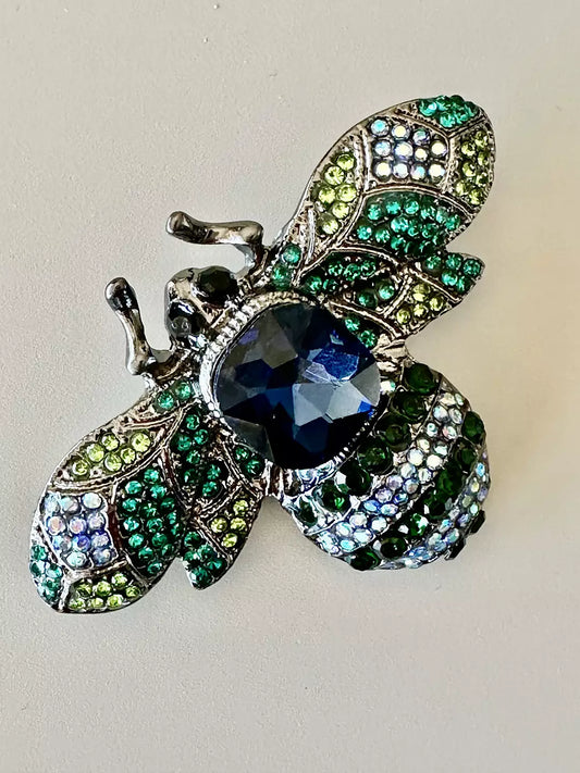 Brosch i form av ett bi med guldfärgade och svarta detaljer, dekorerad med små gnistrande stenar.