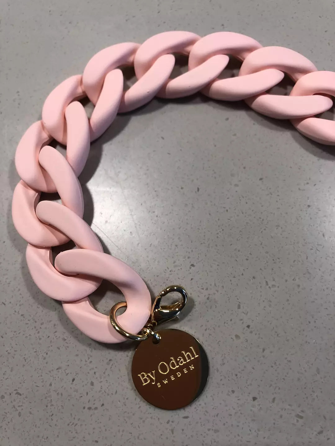 ljusrosa kedjearmband i plast, perfekt att matcha med kedjehalsband.