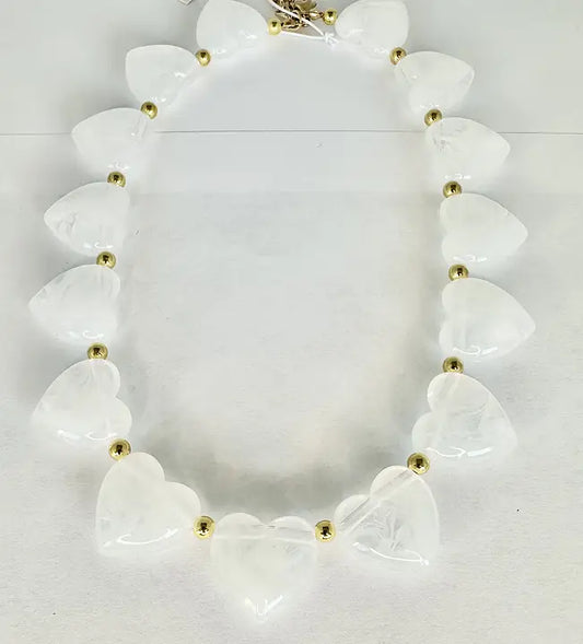 Halsband med vita hjärtformade pärlor och guldfärgade mellandetaljer på ljus bakgrund.