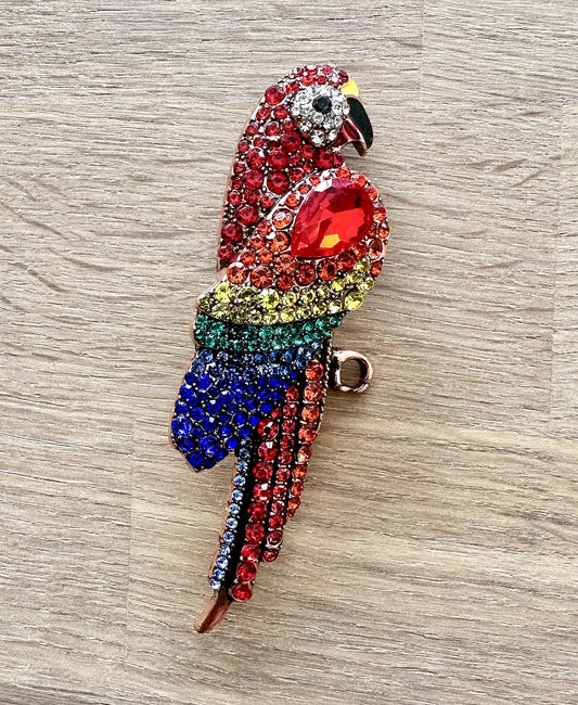 Färgstark glittrande brosch formad som en papegoja med dekorativa stenar i flera färger.