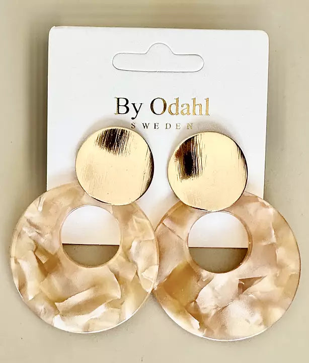 Ett par minimalistiska örhängen i cirkelform med guld och beige färgkombination