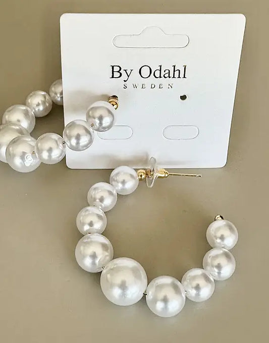 Närbild på örhängen med vita pärlor