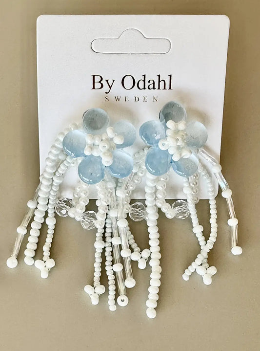 Örhänge med blomformad topp och hängande pärlor i flera rader, visat mot ljus bakgrund