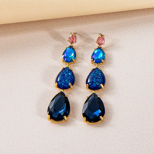 Långa guldpläterade örhängen med blå rhinestones i glas/akryl.