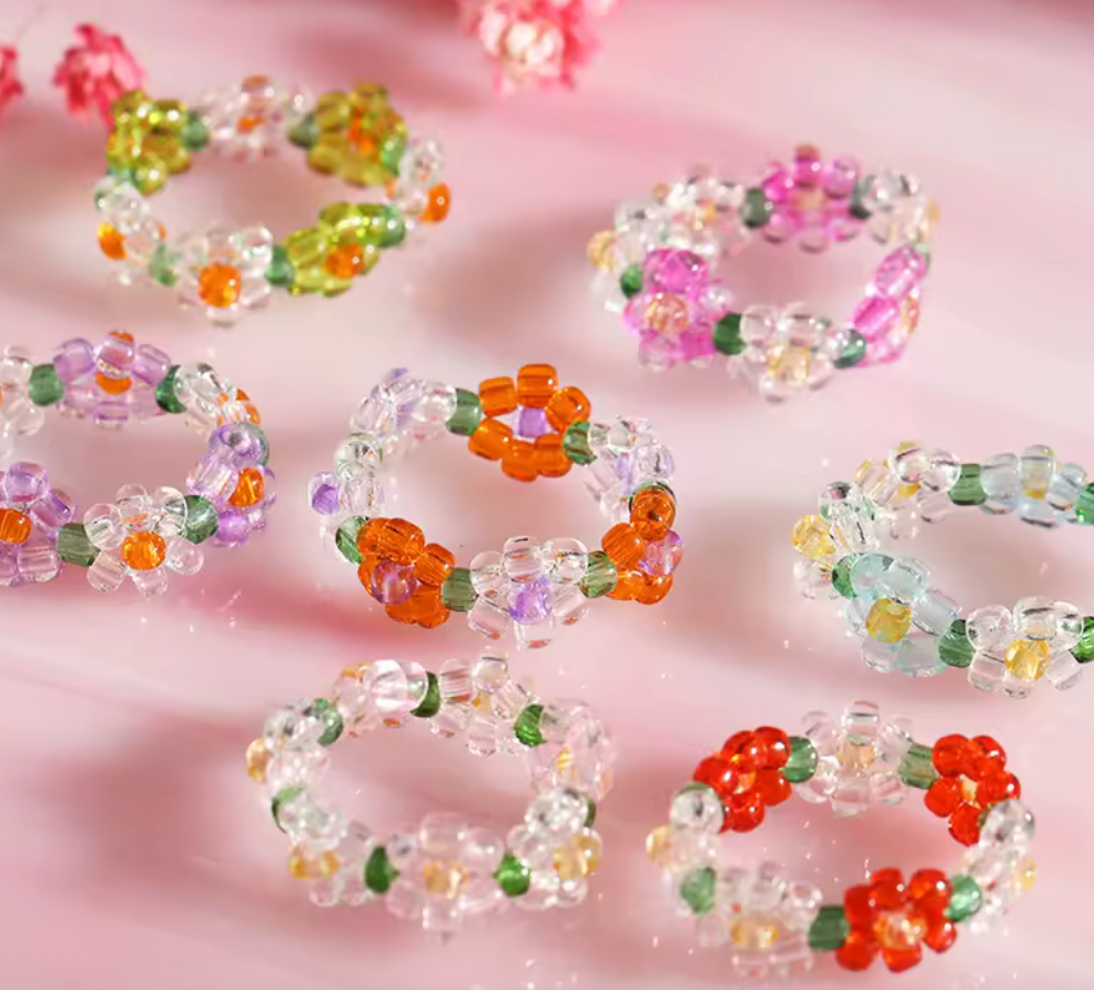 Flera färgkombinationer av elastiska pärlringar med blommotiv.