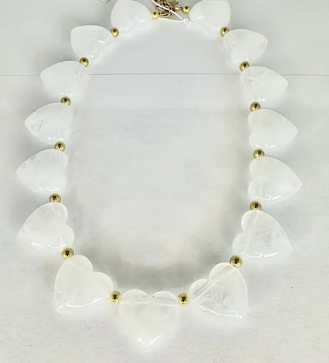 Halsband med vita hjärtformade pärlor och guldfärgade mellandetaljer på ljus bakgrund.