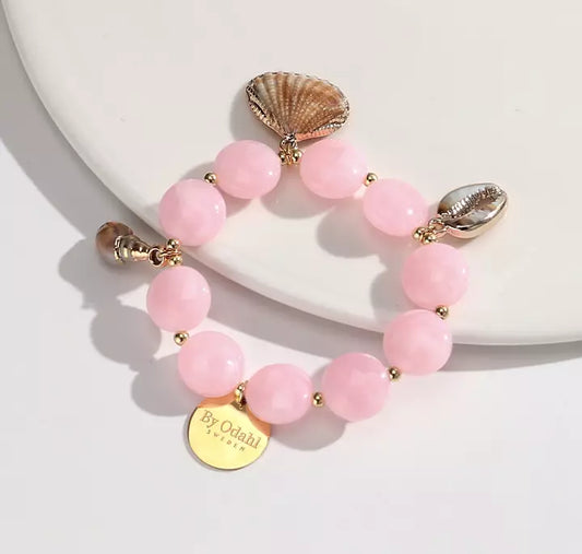 Rosa armband från By Odahl med pärlor och dekorativa snäckor i guldfärgade detaljer.