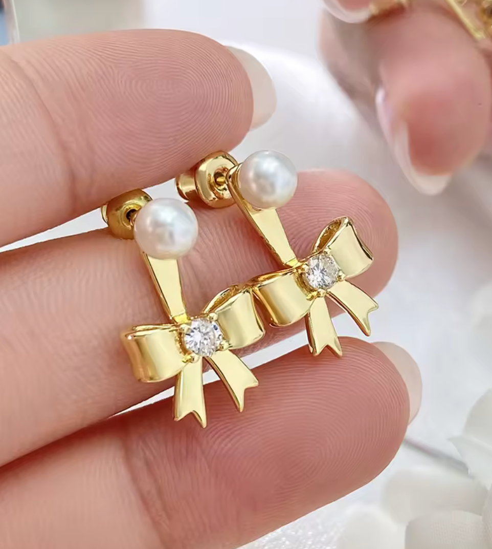 Örhängen i form av en rosett med liten pärla och zirkonsten, tillverkade i guldplätering.