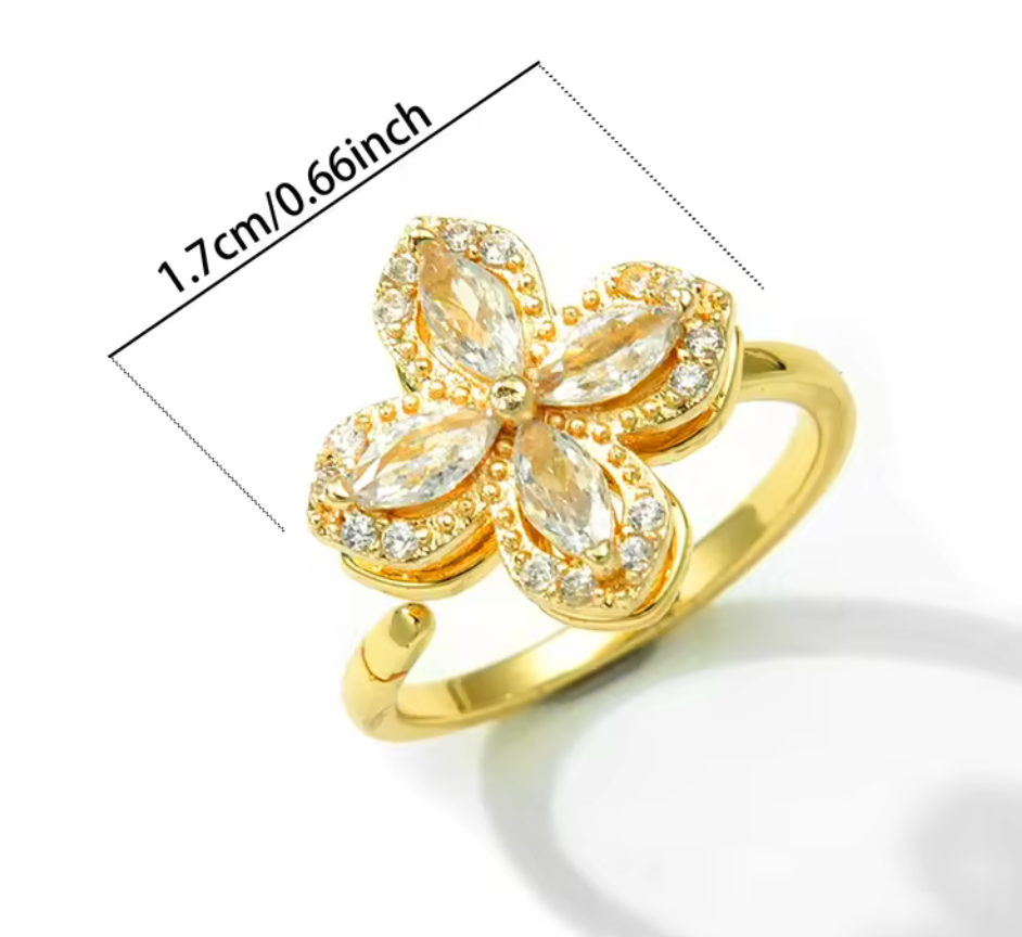 Guldpläterad justerbar ring med fyrbladig blomform av klara zirkonstenar. Toppen är snurrbar.