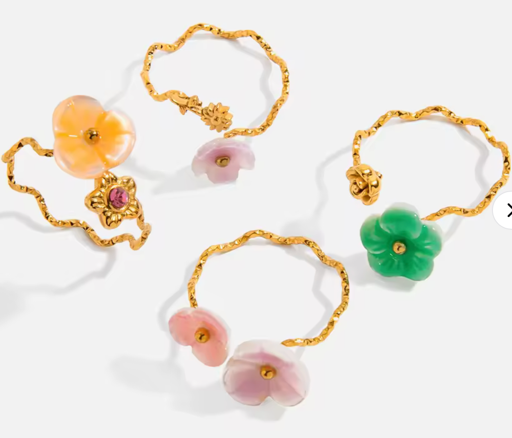 Justerbar guldfärgad ring med blomma i färgat snäckmaterial.