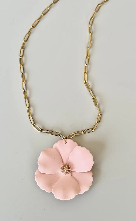 Närbild på halsband med blomma och guldfärgad kedja